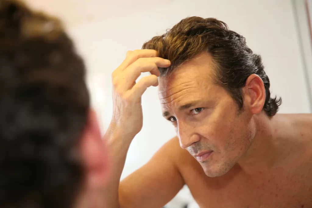 man inspecting his hair in a mirror utc
